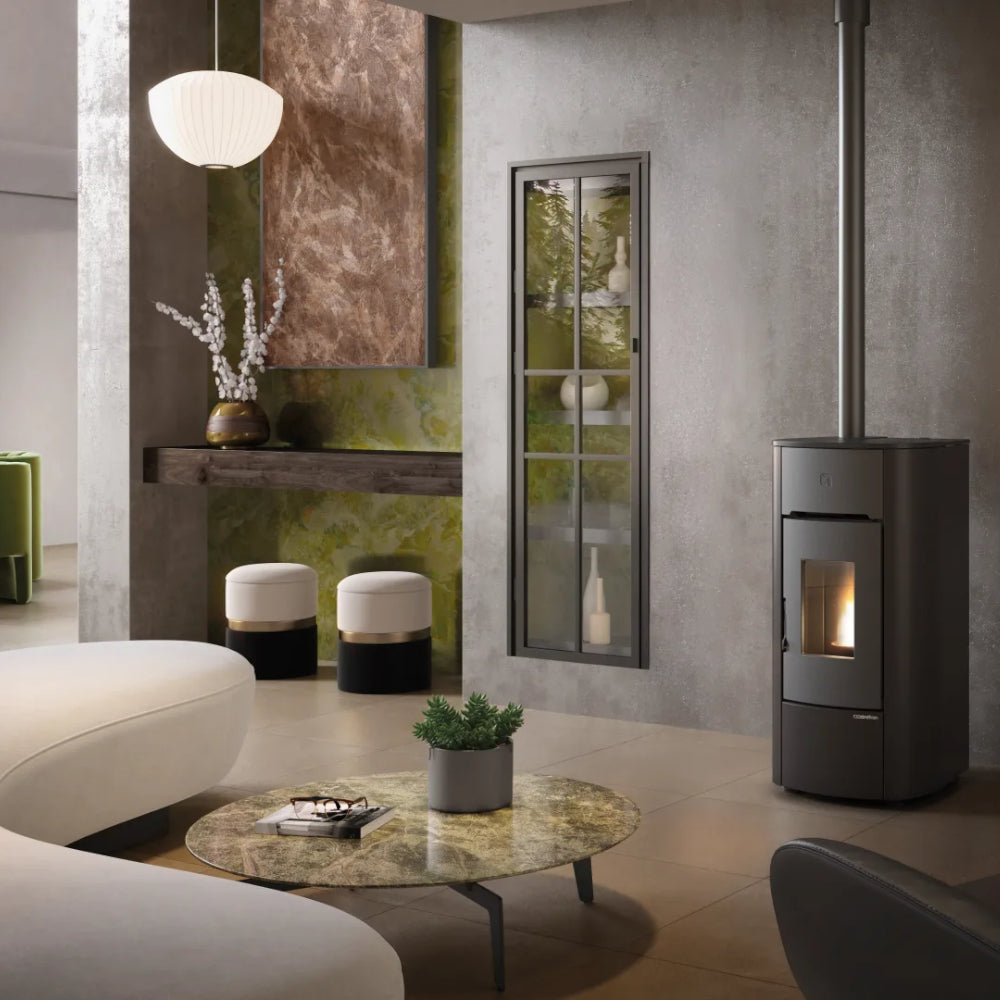 Ambientebild: Extraflame Pelletofen ANGELICA PLUS in Schwarz, in modernem Wohnzimmer neben Fenster, Regal, Hocker und Tisch mit Pflanze | Klimaworld.com
