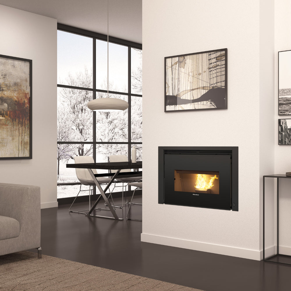 Ambientebild: Extraflame beluefteter Pellet-Kamineinsatz COMFORT P85 in Wand, Feuer hinter Scheibe, Wohnraum mit Tisch | Klimaworld.com
