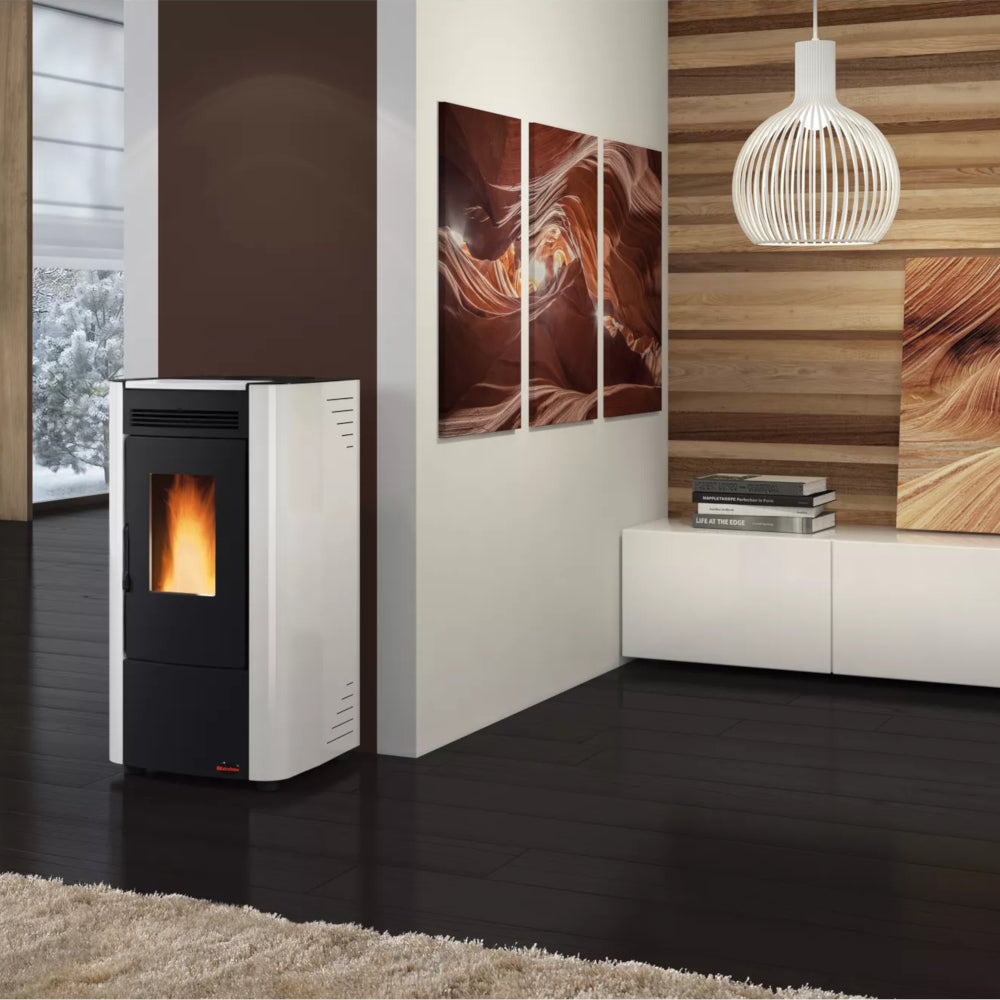 Ambientebild: Extraflame beluefteter Pelletofen KETTY 5.0 in Weiss mit schwarzer Front, Flamme sichtbar, im modernen Wohnraum mit Holzlamellenwand und Bildern | Klimaworld.com