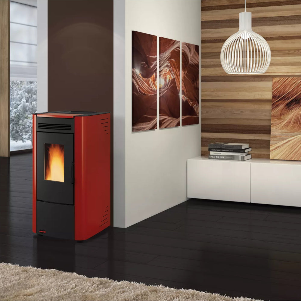 Ambientebild: Extraflame beluefteter Pelletofen KETTY 5.0 in Rot mit schwarzer Front, Flamme sichtbar, im modernen Wohnraum mit Holzlamellenwand und Bildern | Klimaworld.com