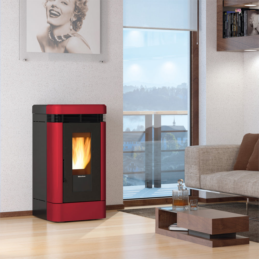 Ambientebild: Extraflame kanalisierter Pelletofen LUCIA PLUS.16 in Rot, in modernem Wohnzimmer neben Sofa und Fenster | Klimaworld.com