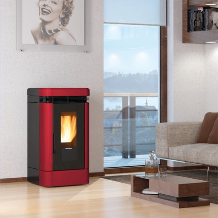 Ambientebild: Extraflame kanalisierter Pelletofen LUCIA PLUS.16 in Rot, in modernem Wohnzimmer neben Sofa und Fenster | Klimaworld.com