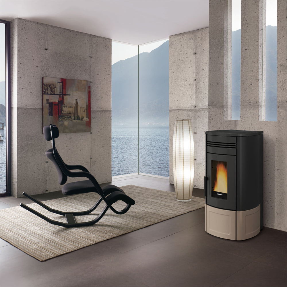 Ambientebild: Extraflame kanalisierter Pelletofen NORIS PLUS LUX in Schwarz-Taupe Majolikaverkleidung; im modernen Wohnraum an Wand neben Fenster, Flamme sichtbar | Klimaworld.com