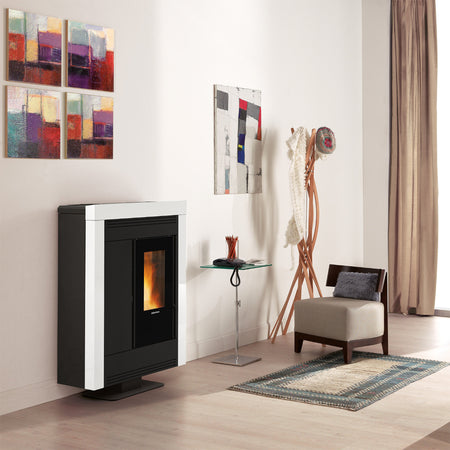 Ambientebild: schmaler Extraflame kanalisierter Pelletofen SOUVENIR PLUS STEEL 5.0 in Weiss; im Wohnraum mit Sessel, Teppich und Wandbildern| Klimaworld.com