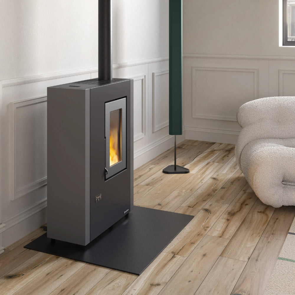 Ambientebild: schmaler Extraflame beluefteter Pelletofen LUISELLA 5.0 Maxi in Wohnraum mit stuckverzierter Wand, Holzboden, schwarz-grauer Korpus | Klimaworld.com