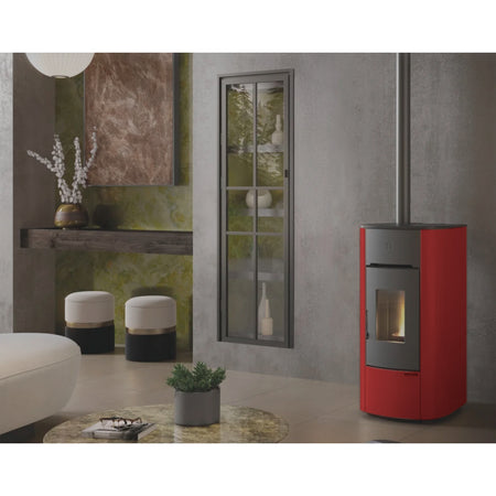 Ambientebild: Extraflame beluefteter Pelletofen ANGELICA EVO in Bordeaux neben Wand mit Fenster, brennende Flamme | Klimaworld.com