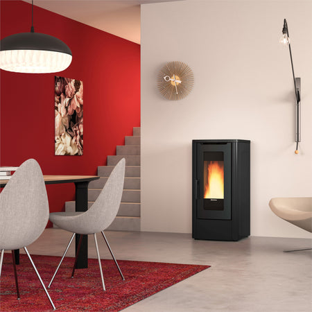 Ambientebild: Extraflame kanalisierter Pelletofen DAHIANA PLUS 5.0 EVO in Schwarz, im Wohnzimmer neben Treppe roter Wand Tisch Stuehlen | Klimaworld.com