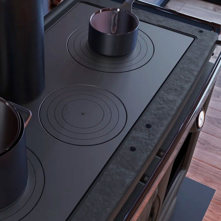 Detailansicht: La Nordica Holzherd ALASKA.16 mit schwarzer Kochplatte und runden Kochfeldern, darauf zwei Toepfe platziert | Klimaworld.com