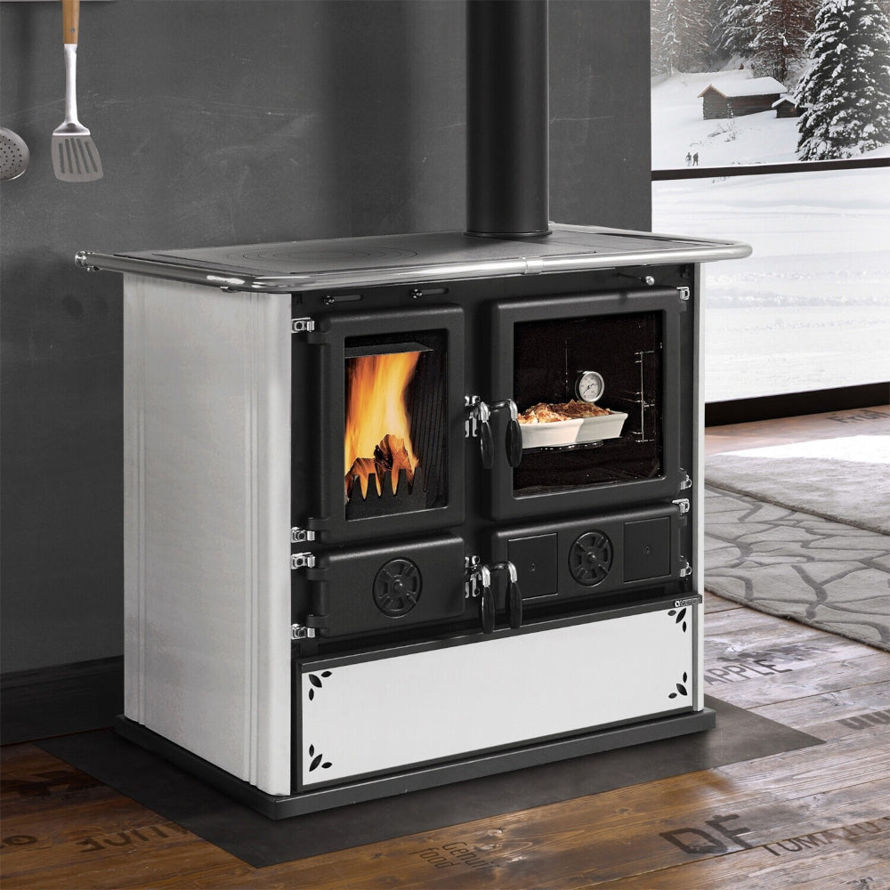 Ambientebild: La Nordica Holzherd Kuechenofen Rosa.16 STEEL, weisse Seiten, schwarze Front, vor Fenster mit Schnee | Klimaworld.com