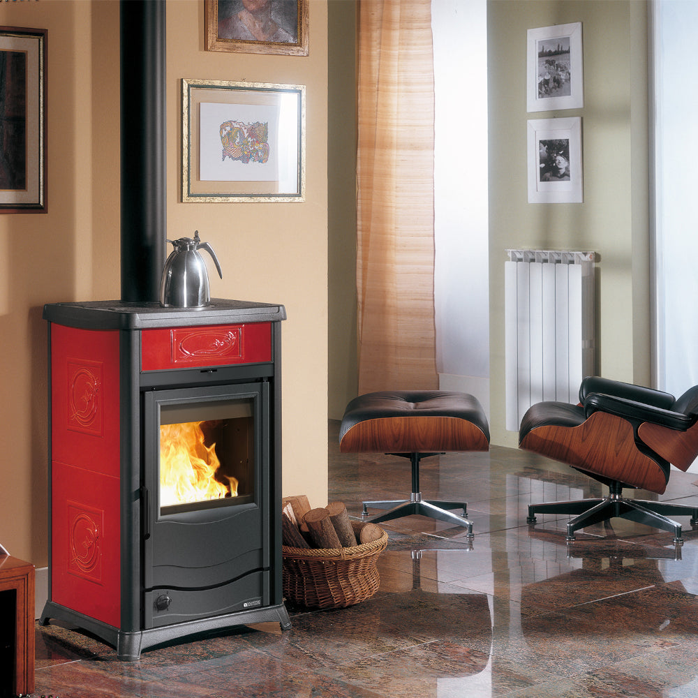 La Nordica Holzofen TERMOROSSELLA PLUS DSA.16 bordeaux mit schwarzer Front, Flamme, Wohnzimmer mit Sessel, Bildern, Heizkoerper | Klimaworld.com