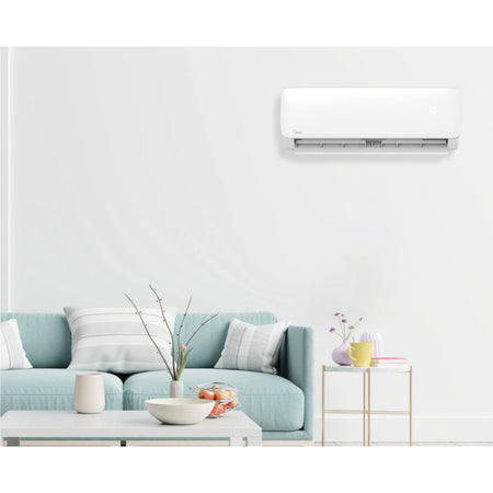 Ambientebild: Midea Xtreme Save Lite, weisses Innengeraet an Wand ueber hellblauem Sofa im Wohnzimmer | Klimaworld.com